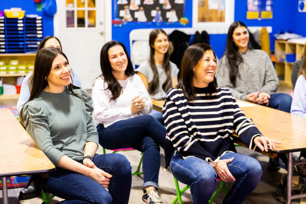 Teachers laughing sitting down together.